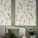 Living room setting with floral wallpaper behind a beige sofa and green pillows under hanging glass pendant lights