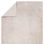 Back corner of rug folded to show cream backing and front abstract design