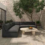 Miles outdoor sofa sectional corner view in courtyard with surrounding plants and stone walls