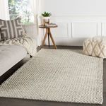 Alta rug styled in modern neutral living room with sofa, side table, and pouf