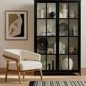 Rolla Outdoor Rug placed in a room setting with cream chair and black cabinet in background
