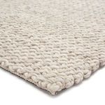Close-up of the chunky wool knit texture and rug edge showing thick yarn loops