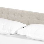 Tufted headboard seen from above with pillows against white bed linens
