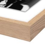 Close-up of natural wood frame corner with white mat around black and white photo