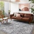 Zion Charcoal Slate rug styled in modern living room with leather sofa, rattan chair, and abstract wall art