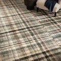 Humphrey Forest Multi Rug under an armchair with black throw and a dark round coffee table with flowers
