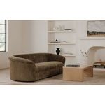 Wider living room scene showing coffee table with sofa and fireplace in soft neutral tones