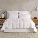 quilt spread on bed with matching cloud white pillows in neutral minimalist bedroom setting