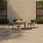 Outdoor patio scene featuring round natural teak outdoor dining table with black strap outdoor chairs