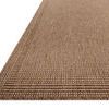 Close-up angled view showing the textured weave and border detail of the Merrick Natural Oatmeal rug.
