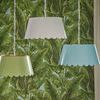 Three Mirasol Pendants in blue, green, and white colors hanging in front of tropical green leaf wallpaper
