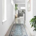 Runner rug positioned in bright hallway with neutral walls and plants