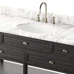 Close-up showing oval undermount sink, aged brass faucet, and marble countertop veining
