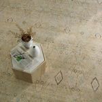 Top view of rug with hexagonal wooden side table topped with white ceramic vases and magazines