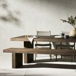Styled dining setup in neutral room featuring the brown wood table and woven chairs