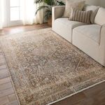 Rug placed on wood floor beside beige sofa with pillows in a bright living room setting