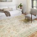Rosette rug styled in bright sitting area with white couch and light gray armchair