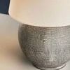 Close-up of textured ceramic base beneath linen shade showing detailed surface finish