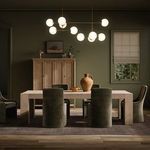 Abaso Dining Table styled in dining room setting with green velvet chairs and modern chandelier
