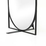 Close-up on the black metal oval mirror frame and rectangular base joint