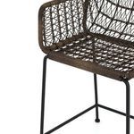 Detailed view of woven wicker seat and connection to black metal frame legs