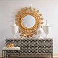 Two gold hammered balls on a patterned black and white console below a gold sunburst mirror