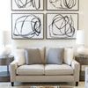Black Circles III painting displayed as one of four framed artworks above a beige couch in a modern living room