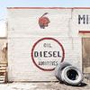 Aerial shot of a high desert Route 66 wall with red Indian head, diesel additives lettering, and tires leaning against whi...