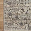 Close-up of rug corner edge laying flat on wood floor, showing faded pattern and straight fringe