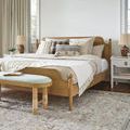 Bedroom scene with Brett lumbar pillow styled on a wooden bed with cream bedding and decorative pillows