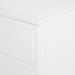 Close-up of upper corner showing beveled edges and smooth white lacquer finish on dresser