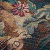 Close-up of tapestry texture highlighting detailed bird and flower motifs in green and brown tones