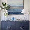 Meredith cabinet in a living space with large abstract blue painting, table lamp, and decorative vases
