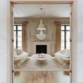 Radcliff pendant hanging centered in living room seen through door frame reflecting in an abstract-shaped wall mirror