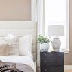 Brushed brass tray styled on a black bedside table with white pillows and a lamp in a bedroom setting