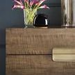Partial close-up showing nightstand drawer front with a glass vase of purple flowers and decorative black object on top