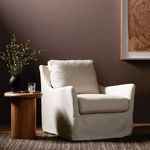 Swivel chair styled in living room with dark wall, wooden side table, and art