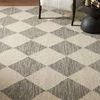 Close-up angled view of Francis rug's diamond pattern showing wool loops and texture with chair leg visible
