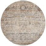 Round rug with a muted taupe and multi-color pattern featuring subtle pile height variation and fringe edges
