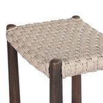 Close-up diagonal view of thick woven rope seat secured to round wood stool legs