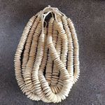 Multiple strands of cream bone disk beads loosely bunched on dark textured stone surface background