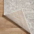 Corner of rug flipped showing textured woven underside against light hardwood flooring
