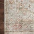Close-up of rug corner on dark wood floor showcasing faded medallion and floral border pattern