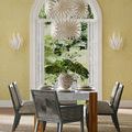 Bismarkia Medium Chandelier hanging in bright yellow dining room with leafy wallpaper and table set