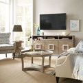 Affinity Entertainment Console in a living room setting with wall-mounted TV, beige carpet, and surrounding furniture
