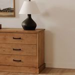 Tade nightstand styled in bedroom with lamp and wall art against white wall