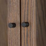Close-up detail of rounded gunmetal cabinet door knobs on wood frame