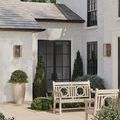 View of outdoor patio space with two antique brass Royster sconces on exterior walls and greenery