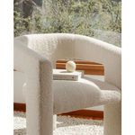 Elo Chair with books and decorative ball resting on seat near large window with greenery outside