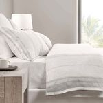 Side view of bed displaying the duvet's subtle stripe pattern and complementing fitted sheet against bright window